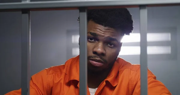 身穿橙色制服的非裔美国人看着摄像机 跪在狱中的脖子上 犯人在狱中服刑 惩教设施或拘留中心的罪犯 肖像视图 — 图库照片