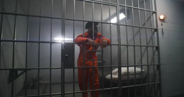 Afrikansk Amerikansk Fånge Orange Uniform Lutar Sig Mot Fängelsets Cellbarer — Stockfoto