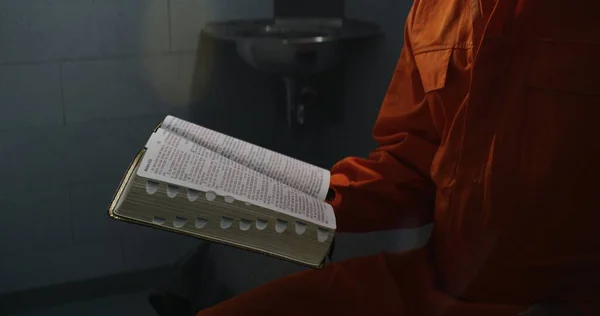 オレンジ色の制服を着たアフリカ系アメリカ人は 刑務所で聖書を読み ページを回します 男性刑事 収容者は刑務所や拘置所で犯罪の刑期を務めている アッラーに対する信仰の概念 — ストック写真