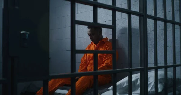Schuldige Afro Amerikaanse Man Oranje Uniform Zit Het Gevangenisbed Denkt — Stockfoto