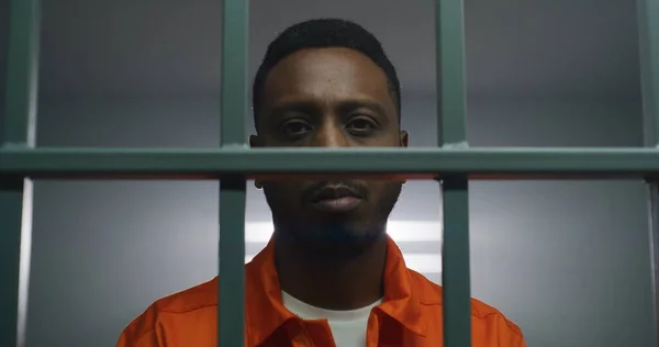 Afroameričan Oranžové Uniformě Drží Ruce Poutech Vězeňských Mřížích Dívá Kamery — Stock fotografie