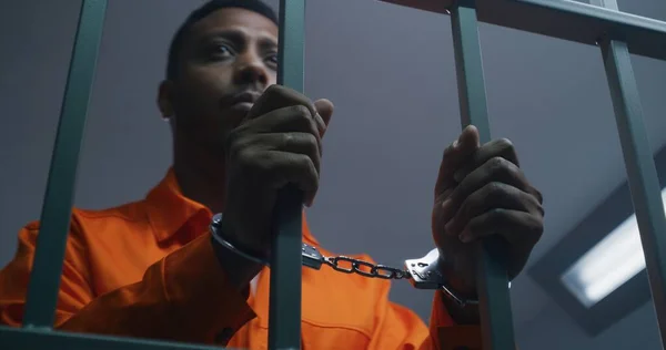 Afroamerikansk Man Orange Uniform Håller Händerna Handbojor Fängelsets Cellstänger Deprimerad — Stockfoto