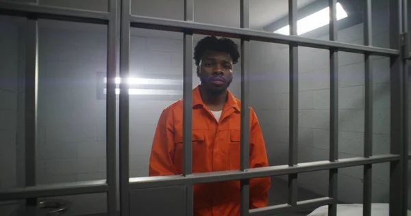 Afro Amerikaanse Man Oranje Uniform Leunt Handen Cel Bars Kijkt — Stockfoto