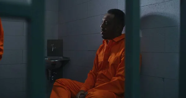 아프리카계 미국인 남자는 침대에 감옥에서 범죄와 이야기 시설에서 오렌지색 유니폼을 — 스톡 사진