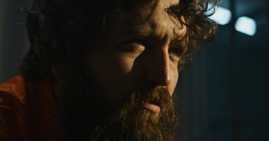 Turuncu üniformalı depresyondaki erkek mahkum hapishane hücresinde oturup sigara içiyor. Tecrit edilmiş suçlu, hapiste suçtan hapis yatıyor. Islah evi. Adalet sistemi. Kapat..