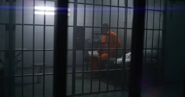 Prigioniero Afroamericano Uniforme Arancione Siede Sul Letto Legge Bibbia Cella — Foto Stock
