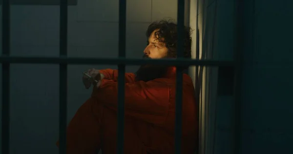 Pensiv Manlig Fånge Orange Uniform Sitter Sängen Röker Cigarett Fängelsecell — Stockfoto