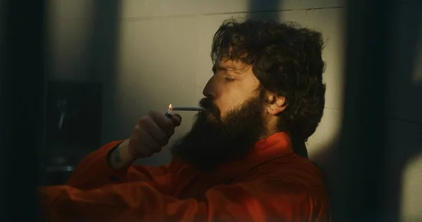 Thoughtful Male Prisoner Orange Uniform Sits Bed Lights Cigarette Lighter — Stock Photo, Image