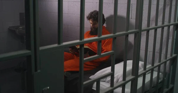 Männlicher Häftling Orangefarbener Uniform Sitzt Auf Dem Bett Liest Bibel — Stockfoto