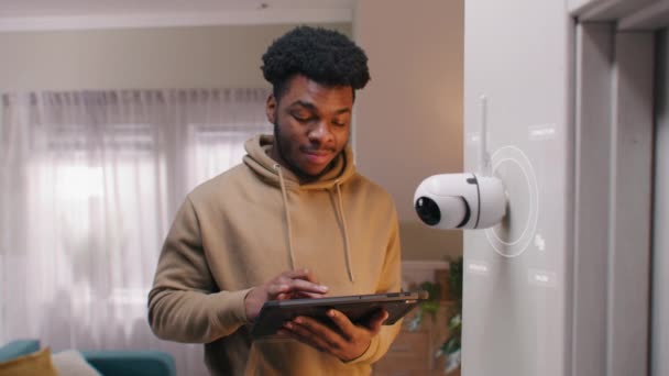 アフリカ系アメリカ人男性は デジタルタブレットを使用して自宅でAi認識を備えたセキュリティカメラを設置しています 3D円レンダリングはCctvカメラとの無線インターネット接続を示します Vfxアニメーション モニタリングシステム — ストック動画