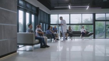 Muhtelif insanlar klinik lobisindeki koltuklarda oturur, doktor randevusunu beklerler. Doktor hastalarla tıbbi muayene ve test sonuçları hakkında konuşur. Modern tıp merkezinde bekleme odası. Sağlık Hizmetleri.