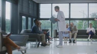 Muhtelif insanlar klinik lobisindeki koltuklarda oturur, doktordan randevu beklerler. Doktor, çok ırklı çiftlerle tıbbi test sonuçları hakkında konuşuyor. Modern tıp merkezinde bekleme alanı. Sağlık Hizmetleri.