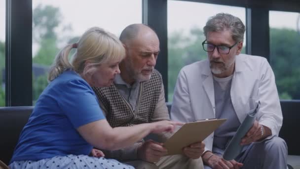 Starší Pár Sedí Pohovce Hale Kliniky Návštěvě Lékaře Doktor Mluví — Stock video