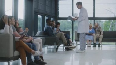 Çeşitli insanlar klinik lobisindeki koltuklarda oturur, doktor ya da tıbbi test sonuçları için randevu beklerler. Doktorlar hastalara gelir ve konuşurlar. Modern tıp merkezinde bekleme alanı. Sağlık hizmetleri sistemi.