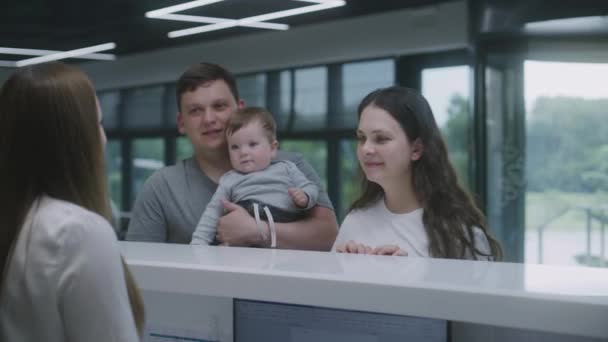 Rodina Dítětem Přichází Recepci Hale Kliniky Administrátorka Konzultuje Lidi Dává — Stock video