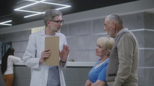 Ein Älteres Ehepaar Steht Mit Einem Arzt Der Lobby Der — Stockvideo