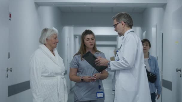 Gammal Läkare Står Kliniken Korridor Med Sjuksköterska Och Patient Professionella — Stockvideo