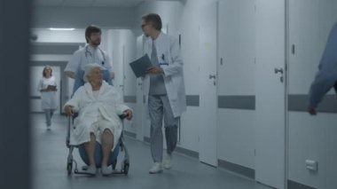 Doktor, kadın hasta klinik koridorunda yürürken tekerlekli sandalyeyi itiyor. Doktorlar yaşlı kadını ameliyata ya da ameliyathaneye götürürler. Hastane koridorunda tıbbi personel ve hasta var..