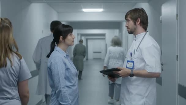 Homme Médecin Tient Dans Couloir Clinique Avec Patiente Utilise Tablette — Video