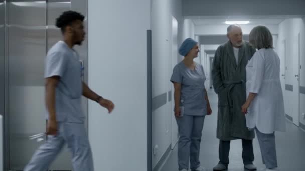 Медсестра Уніформі Вигулює Лікарняний Коридор Старим Чоловіком Приходить Підняти Двері — стокове відео