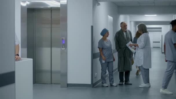 Infermiera Uniforme Cammina Corridoio Ospedale Con Uomo Anziano Entra Ascensore — Video Stock