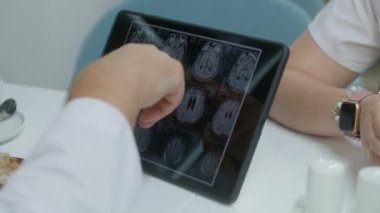 Profesyonel doktor hastane kafesindeki dijital tablet bilgisayardaki MRI veya CT görüntülerine bakıyor. Doktor, hastanın beyin tarama sonuçlarını inceliyor. Sağlık personeli klinik kafeteryasında fren yaptı..
