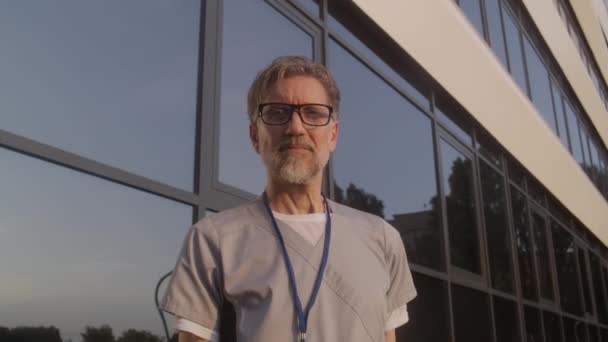 Starší Doktor Uniformě Stojí Venku Vchodu Nemocnice Profesionální Zdravotník Brýlích — Stock video