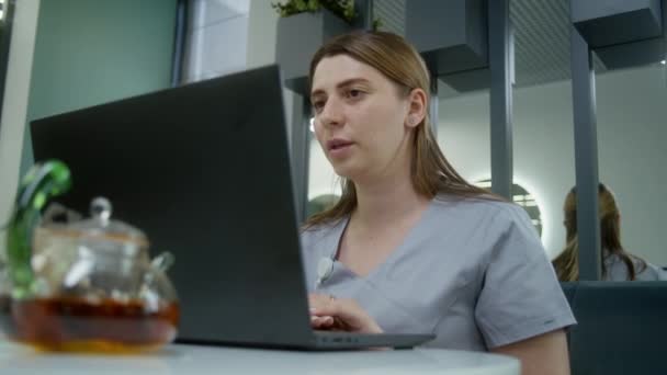 의사는 진료소 카페에 앉아서 노트북을 사용합니다 전문가 채팅을 환자와 온라인 — 비디오