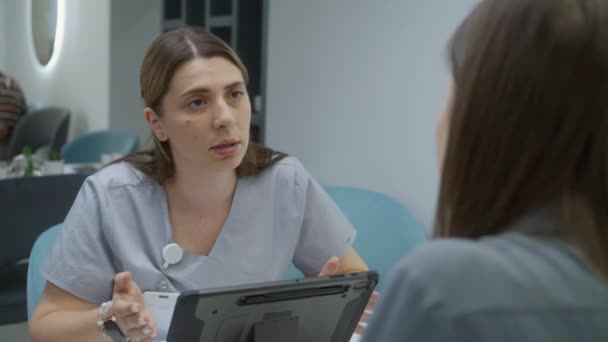 Naislääkäri Istuu Klinikan Kahvilassa Tapaamisessa Potilaan Kanssa Käyttää Digitaalista Tablet — kuvapankkivideo