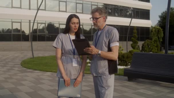 Zwei Ärzte Stehen Draußen Und Besprechen Die Behandlung Der Patienten — Stockvideo