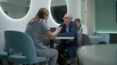Kadın doktor klinikte yaşlı bir hastayla oturuyor. Profesyonel doktor, tıbbi tanı sonuçlarını adamla tartışıyor. MRI beyin taraması görüntülü dijital tablet. Hastane ya da Tıp Merkezi kantini.