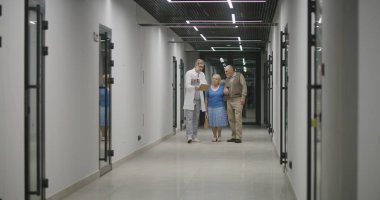 Yaşlı çift klinik koridorunda doktorla yürüyor. Doktor hastalarla konuşur, tıbbi muayene ya da test sonuçlarını tartışır. Sağlık personeli ve hastane ya da tıp merkezindeki insanlar. Sağlık Hizmetleri.