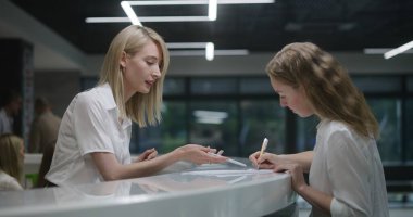 Bayan yönetici, klinik lobisindeki resepsiyonda hastayla konuşuyor. Kadın danışman, hastanede evrakları doldurmaya yardım ediyor. Tıp personeli modern tıp merkezinde çalışıyor. Sağlık hizmetleri.