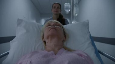 Hemşire yaşlı hastayı tıp merkezi koridorundaki cerrahi bloğuna götürüyor. Eldelry denen kadın sedyede solunum tüpüyle yatıyor ve ameliyattan önce uyuyor. Modern hastanede çalışan tıbbi personel.