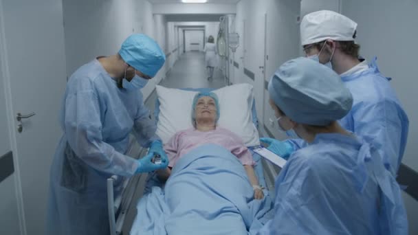 护士和护理人员在医疗设施走廊检查生病的老年妇女 医生检查病人手上的脉搏血氧计 医护人员在急诊室工作 放大点 — 图库视频影像