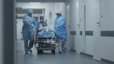 Doktorlar, hemşireler ve sağlık görevlileri hastayla birlikte sedyeyi ameliyathaneye götürün ve ona destek olun. Çok hasta bir hasta sedyede yatıyor. Acil serviste tıbbi personel var..