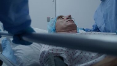 Cerrahlar yaşlı ve ağır hasta bir adamla sedyeyi ameliyathaneye götürürler. Hemşire ve sağlık görevlileri hemen tıbbi tesisin koridorlarını kapatın. Acil serviste çalışan tıbbi personel. Ağır çekim.