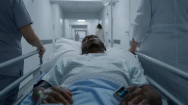 Afrika kökenli Amerikalı hasta ciddi bir ameliyattan sonra venöz kateter ve nabız oksimetresiyle sedyede uyuyor. Doktor ve hemşire orta yaşlı adamı hastane odasına naklediyor. Sıhhiye hayat kurtarır.