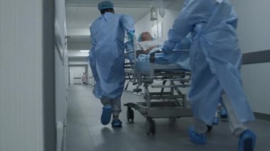 Doktorlar, hemşireler ve sağlık görevlileri, ağır yaralı hastalarla birlikte sedyeyi ameliyathaneye götürün. Acil serviste tıbbi personel insan hayatını kurtarıyor. Tıbbi tesis koridoru. Yavaş çekim.