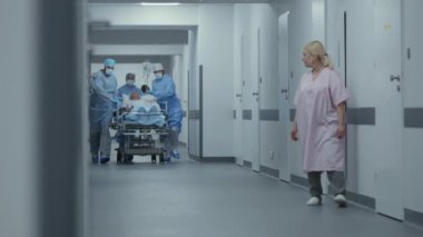 Doktorlar ve hemşireler yaralı bir hastayla sedyeyi ameliyathaneye götürürler. Profesyonel tıbbi personel acil serviste insan hayatını kurtarıyor. Tıbbi tesis koridoru. Yavaş çekim.