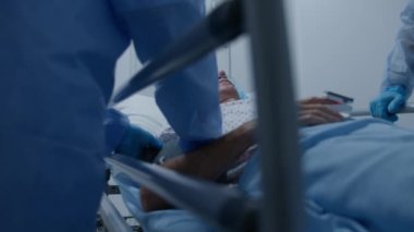 Yaşlı bir adam tıbbi tesis koridorunda sedyede yatıyor. Doktor ağır hasta muayenesi yapıyor ve kan basıncını ölçüyor. Personel acil servisi. Ağır çekim. Kapat..