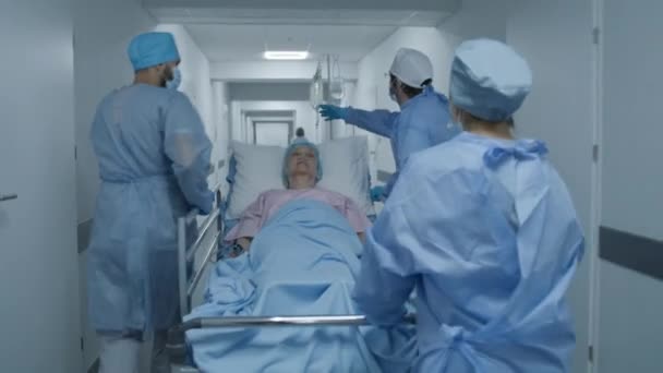 护士和医护人员把病人的担架推入手术室 老年妇女躺在格尔内 身上滴了点药 应急部门的人员工作 后视镜跟踪射击 — 图库视频影像