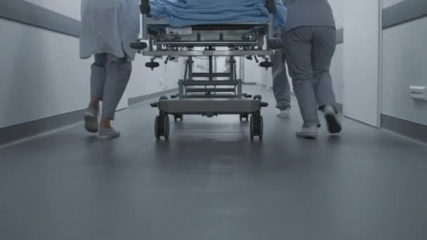 医生和护士把重伤员的担架推入手术室 医疗拯救了人的生命 靠近医护人员的腿 明亮的医疗设施走廊 慢动作 — 图库视频影像