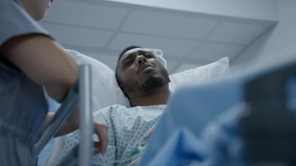 非裔美国人躺在担架上 在动手术前与医生交谈 医生站在格尔内附近 使医疗中心的病人平静下来 医护人员在急诊室工作 靠近点 — 图库视频影像