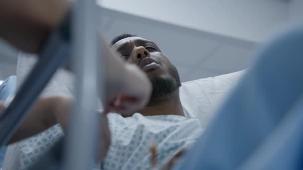 非洲裔美国人躺在格尔内 在动手术前与医生交谈 医生站在靠近担架的地方 病人在医疗中心 医护人员在急诊室工作 靠近点 — 图库视频影像