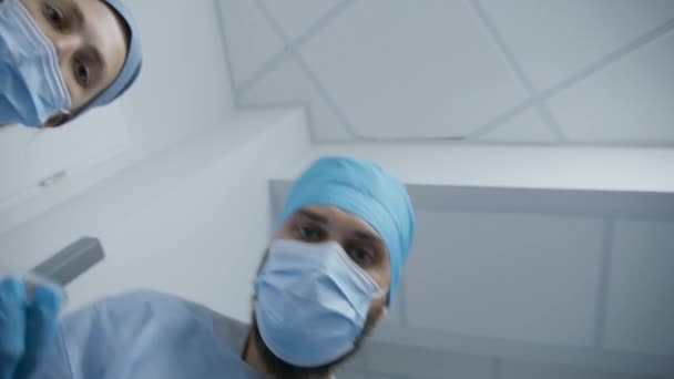 非裔美国医生耐心地谈论移解问题 与女同事一起的成年医生放置了呼吸管和滴注 专业外科医生带男人到医院走廊去做手术 — 图库视频影像