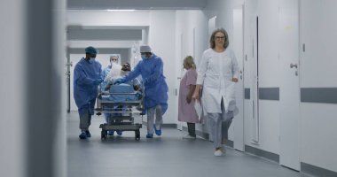 Doktorlar ve hemşireler yaralı bir hastayla sedyeyi ameliyathaneye götürürler. Profesyonel tıbbi personel acil serviste insan hayatını kurtarıyor. Tıbbi tesis koridoru. Yavaş çekim.