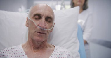 Kıdemli hasta sedyede serumla oturur, tüp yutar ve uyur. Kadın doktor, yaşlı adamı sedyede hastane koğuşuna itiyor. Modern klinikte çalışan tıbbi personel.