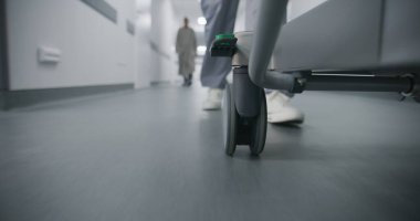 Doktor, hemşire ya da sağlık görevlisi ağır yaralı bir hastayla sedyeyi ameliyathaneye taşıyın. Sıhhiyeci insan hayatını kurtardı. Tıbbi personel bacaklarını kapatın. Parlak tıbbi tesis koridoru. Acil servis..