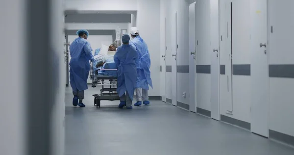 간호사 구급대원들이 환자를 수술실로 밀어붙입니다 보조기를 아프리카계 미국인 남자는 구르니에 — 스톡 사진